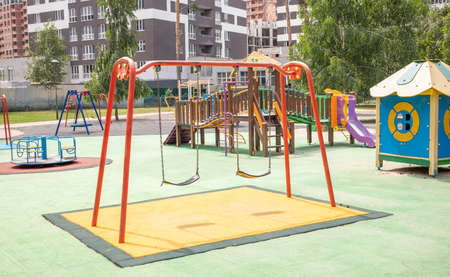 A colorful modern playground in the courtyard in a park without people. Swing, outdoor carousel for...