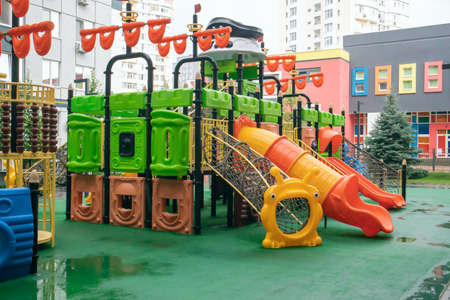 A courtyard of high-rise buildings with a new modern colorful and large playground on a rainy summer...
