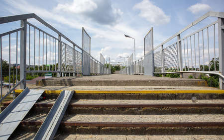 Railway bridge with steps, with impressive steps in perspective. Overhead pedestrian crossing. Bridge stairs connecting one platform to another at the train stationの写真素材