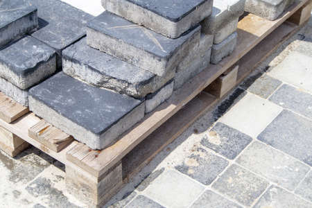 Concrete or paved gray paving slabs or floor or walkway stones stacked on a pallet. Concrete paving slabs in the backyard or road paving. Garden brick path in the courtyard on a sandy foundationの写真素材
