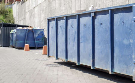 Metal durable blue industrial trash bin for outdoor trash at construction site. Large waste basket for household or industrial waste. A pile of wasteの写真素材