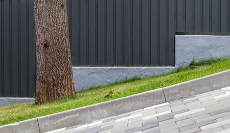 A long descent covered with gray paving slabs. The ramp is paved with concrete tiles. Wheelchair and...