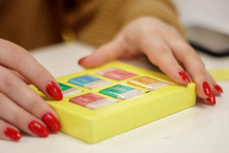 Women's hands open a small yellow box with chocolates or chocolate bars. The concept of love for holiday food gifts. Sweets at the Roshen chocolate factory. Ukraine, Kiev - February 09, 2022のeditorial素材