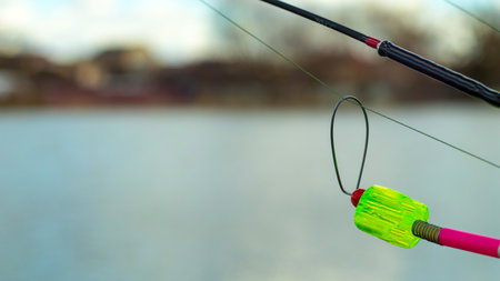The bite alarm hangs on a fishing rod against the background of water. Fishing rod while fishing on...