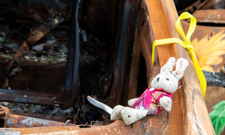 Close-up of a childs toy in ruins after a fire. A soft toy among the cars that burned down as a result of the bombing. A ruined childhood. War concept. Ukraine. Dangerous traffic accident.の写真素材