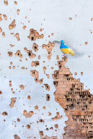 Shelled wall with a drawing of a dove in the colors of the flag of ukraine, blue and yellow. The dove is a symbol of purity, light, peace, love, the human soul. Ukraine, Kyiv - May 06, 2023.のeditorial素材