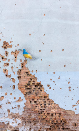 Shelled wall with a drawing of a dove in the colors of the flag of ukraine, blue and yellow. The dove is a symbol of purity, light, peace, love, the human soul. Ukraine, Kyiv - May 06, 2023.のeditorial素材