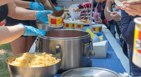 Tomato soup with pasta is a Polish dish. Zupa pomidorowa. Hot soup made from grated tomatoes. People and tourists walk, eat and buy food at the street food festival. Ukraine, Kyiv - August 17, 2023.のeditorial素材