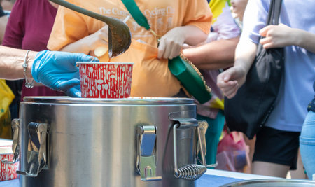 Tomato soup with pasta is a Polish dish. Zupa pomidorowa. Hot soup made from grated tomatoes. People and tourists walk, eat and buy food at the street food festival. Ukraine, Kyiv - August 17, 2023.のeditorial素材
