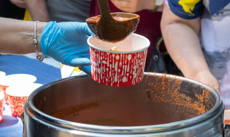 Tomato soup with pasta is a Polish dish. Zupa pomidorowa. Hot soup made from grated tomatoes. People and tourists walk, eat and buy food at the street food festival. Ukraine, Kyiv - August 17, 2023.のeditorial素材