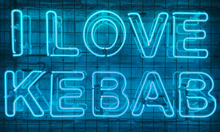 Neon shining sign in blue color on a brick wall with the inscription or slogan I love kebab. Brick wall, background. Bright electric neon light. Cafe-restaurant Doner Kebabの写真素材