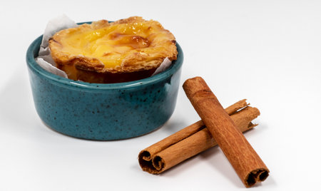 Pastel de nata tarts or Portuguese egg tart and cinnamon sticks isolated on white background. Pastel...