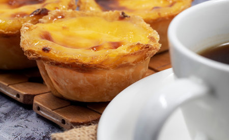 Lots of desserts Pastel de nata or Portuguese egg tart with a white cup of black coffee. Pastel de...