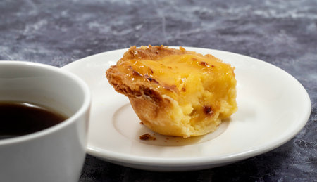 One uneaten Pastel de nata or Portuguese egg dessert on a white plate. Pastel de Belm is a small pie...