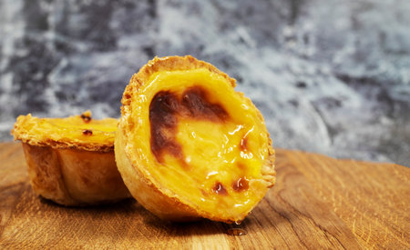 Pastel de nata tarts or Portuguese egg tart on a wooden brown background. Pastel de Belem is a small...