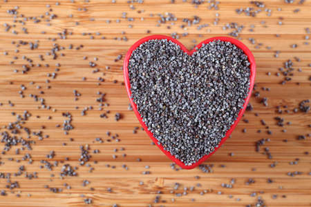 Poppy seeds in a heart bowl. Close-up.の写真素材
