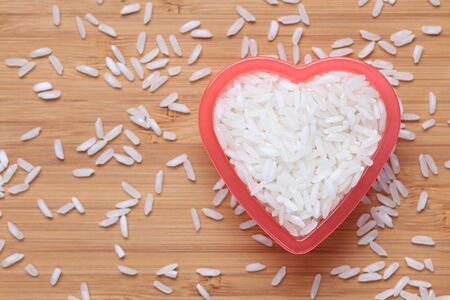 White rice heap in a heart bowl. Close-up.の写真素材