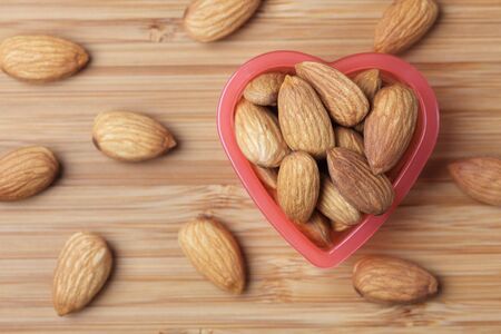 Almonds in a heart bowl. Close-up.の写真素材