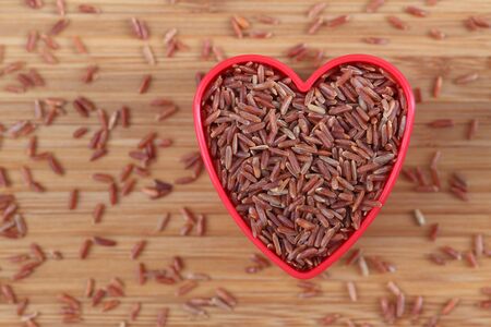 Red rice in a heart shape bowl. Close-up.の写真素材