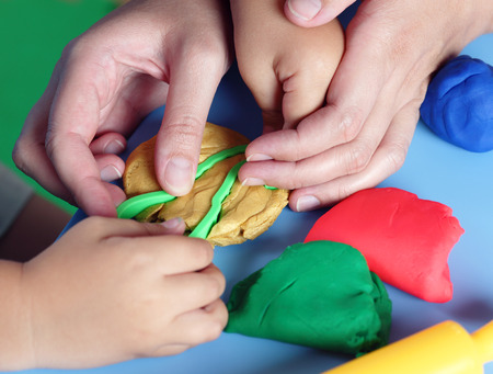 Children's and mother's hands playing with playdough.の写真素材
