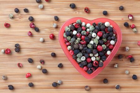 Mixed peppercorns in a heart bowl. Close-up.の写真素材