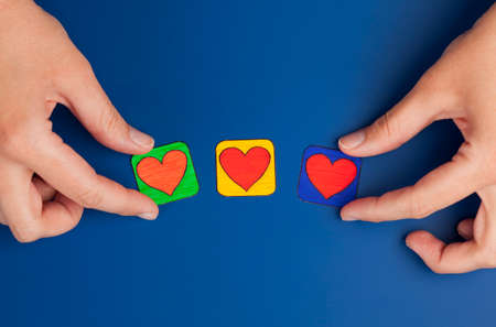 Three hearts on blue background with woman's hands. Heart drawn by me.の写真素材