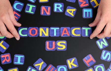 Words \"Contact us\" spell out on black with woman\'s hands and letters. Letters drawn by me.の写真素材