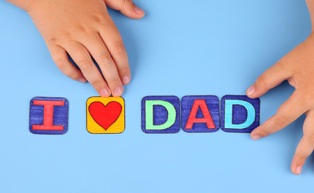 \"I love dad\" spell out on blue with child\'s hands. Letters drawn by me.の写真素材