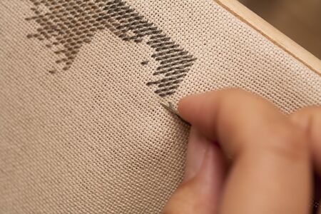 Woman's hand with needle making cross-stitch.の写真素材