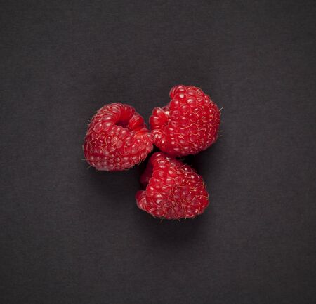 Three raspberries on black background. Top viewの写真素材