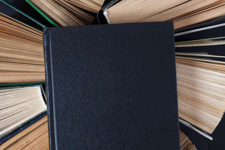 Top view of old hardback books with black book on top.