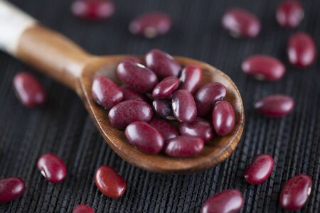 Red kidney beans in a wooden spoon on black napkin.の写真素材