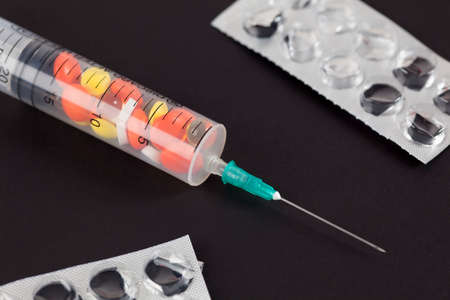 Syringe with pills and empty blister on black background.の写真素材