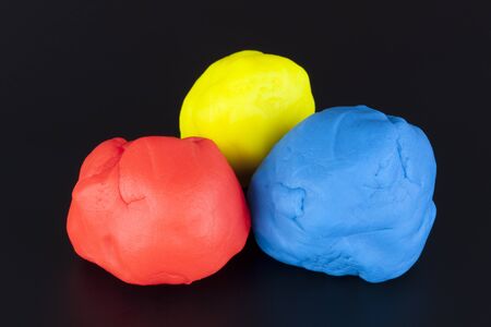 Colorful child's play clay (Red, Yellow, Blue) on black background.の写真素材