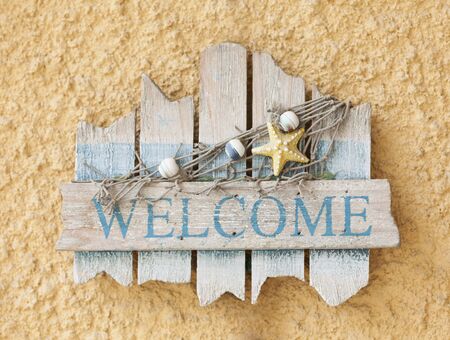Wooden sign "Welcome" on yellow stone backgroundの写真素材