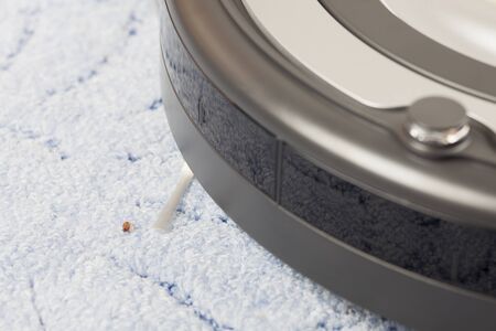 Vacuum Cleaning Robot on blue carpet with crumb.の写真素材