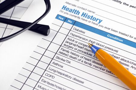 Health History form with glasses and ballpoint pen.の写真素材