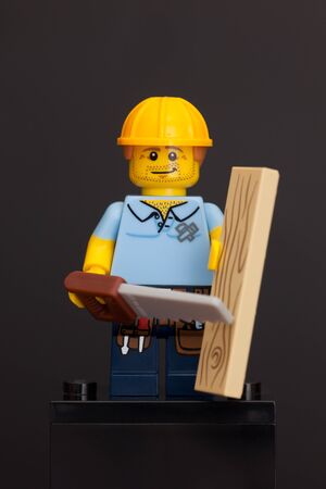Tambov, Russian Federation - June 08, 2015 LEGO carpenter mini figure with wooden plank saw on black . Studio shot.のeditorial素材