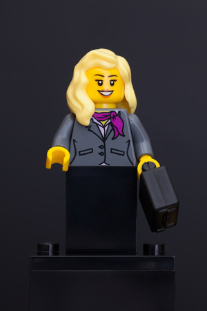 Tambov, Russian Federation - June 08, 2015 Lego businesswoman minifigure with black suitcase on black background. Studio shot.のeditorial素材