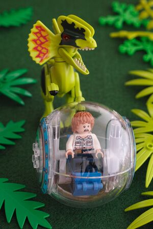 Tambov, Russian Federation - June 24, 2015 Lego Jurassic park. Gray minifigure in a gyrosphere being chased by a dilophosaurus. Studio shot.のeditorial素材