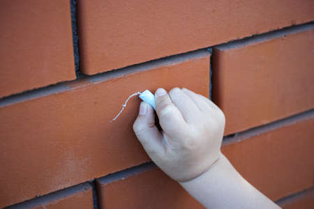 Childs hand with chalk drawing on the brick wallの写真素材