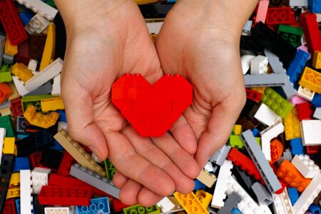 Tambov, Russian Federation - September 07, 2015 Lego red heart in woman hands with Lego blocks background. Studio shot.のeditorial素材