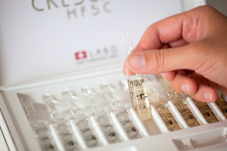 Paphos, Cyprus - November 13, 2015 Woman hand with ampoule of Crescina Re-Growth in front of Crescina HFSC 100% complete treatment box. Shallow depth of field. Crescina HFSC preserves cell longevity, fights against ageing and promotes the physiological haのeditorial素材