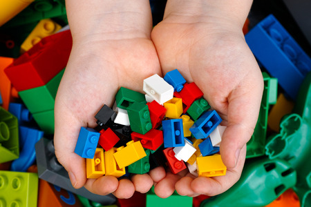 Tambov, Russian Federation - February 20, 2015 Lego Bricks in childs hands with Lego Duplo blocks and toys background. Studio shot.のeditorial素材