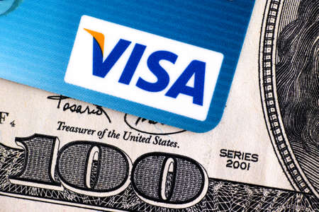 Tambov, Russian Federation - April 02, 2016 Visa logo on credit card and 100 dollar bill. Studio...