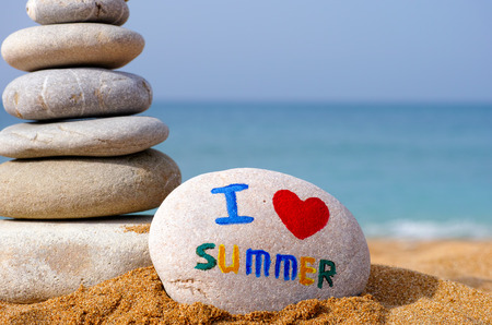 Stack of stones on the sea beach with one stone with symbol I, heart, summer.の写真素材