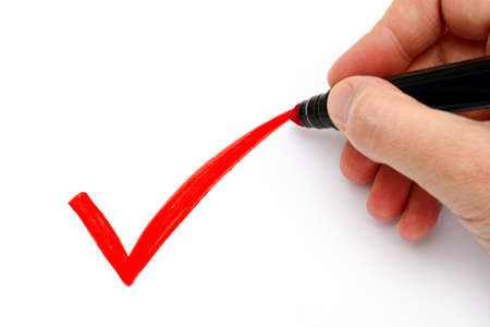 Woman hand with marker drawing red check mark on white background.