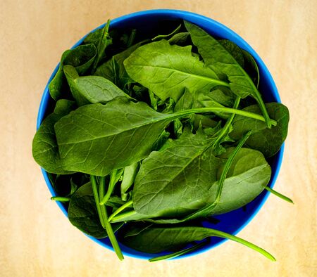Fresh spinach in blue bowl.