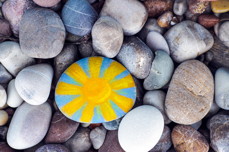 Bright sun painted on pebble with stones background.の写真素材