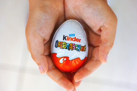 Paphos, Cyprus - November 21, 2016 Child hands with Kinder Surprise egg. Word Surprise written in German. Manufactured by Italian company Ferrero.のeditorial素材